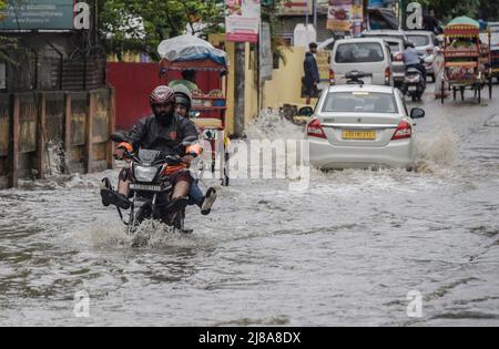 Pendler machen sich am 14. Mai 2022 in Guwahati, Indien, nach starken Regenfällen auf einer Wasserstrasse auf den Weg. Ein schlechtes Entwässerungssystem ist ein Hauptgrund für die Wasserabführung in indischen Städten. Quelle: David Talukdar/Alamy Live News Stockfoto