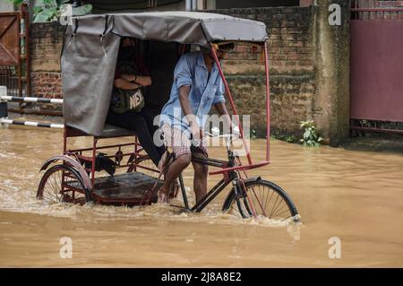 Pendler machen sich am 14. Mai 2022 in Guwahati, Indien, nach starken Regenfällen auf einer Wasserstrasse auf den Weg. Ein schlechtes Entwässerungssystem ist ein Hauptgrund für die Wasserabführung in indischen Städten. Quelle: David Talukdar/Alamy Live News Stockfoto