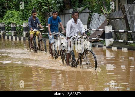 Pendler machen sich am 14. Mai 2022 in Guwahati, Indien, nach starken Regenfällen auf einer Wasserstrasse auf den Weg. Ein schlechtes Entwässerungssystem ist ein Hauptgrund für die Wasserabführung in indischen Städten. Quelle: David Talukdar/Alamy Live News Stockfoto