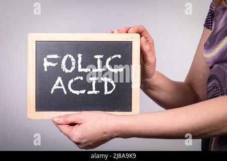 Folsäure. Frau mit einem Kreidetafel mit Text. Stockfoto