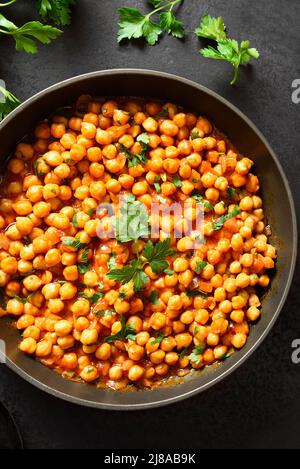 Knusprig geröstete Kichererbsen. Gericht im indischen Stil über schwarzem Stein Hintergrund. Vegetarisches veganes Food Konzept. Draufsicht, flaches Lay Stockfoto