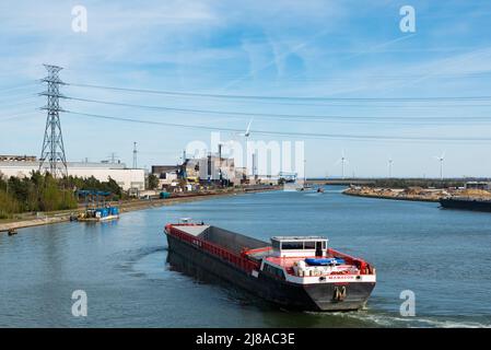 Genk, Limburg, Belgien - 04 12 2022 - Industrietätigkeit und ein von Windmühlen angetriebenes elektronisches Werk am Ufer des Albert-Kanals Stockfoto