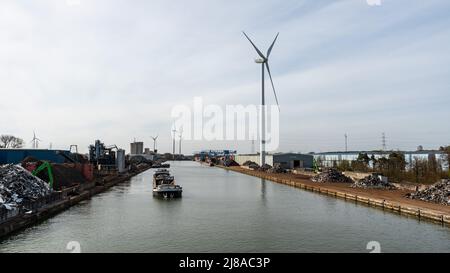 Genk, Limburg, Belgien - 04 12 2022 - Industrietätigkeit und ein von Windmühlen angetriebenes elektronisches Werk am Ufer des Albert-Kanals Stockfoto