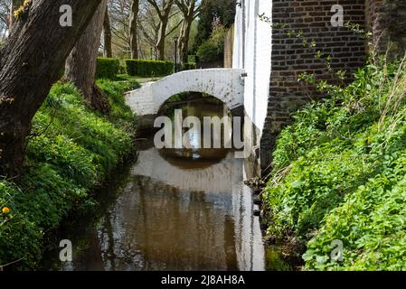 Thorn, Limburg, Niederlande, 04 08 2022 - Bach in den Hinterhöfen von historischen Häusern mit einer reflektierenden Fußgängerbrücke Stockfoto