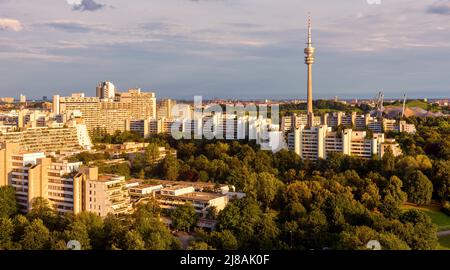 Skyline von München bei Sonnenuntergang, Deutschland, Europa. Panorama des grünen Olympiaparks und des Dorfes im Sommer, Stadtlandschaft München mit Fernsehturm. Landschaftlich schöne V Stockfoto