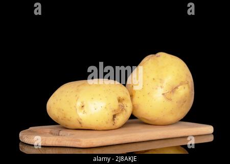Zwei rohe Bio-Kartoffeln auf einem Holzschneidebrett, Nahaufnahme, isoliert auf schwarzem Hintergrund. Stockfoto
