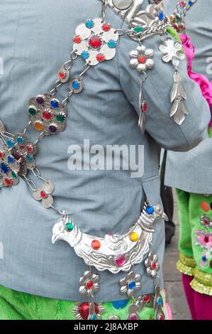 Lima, Peru; 09092012: Nahaufnahme von wunderschönen Silberornamenten auf traditionellen peruanischen Kleidern, Mann von hinten gesehen, mit grauer Jacke und grünem tro Stockfoto