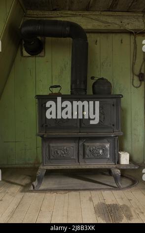 Antiker gusseiserner Holzofen in der Küche im alten, um 1730 erdalten französischen Regime Maison Drouin, Sainte-Famille, Ile d'Orleans, Quebec, Kanada. Stockfoto