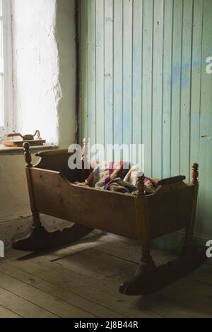 Antike Schaukelkrippe im Schlafzimmer im alten, um 1730 erdierten französischen Regime Maison Drouin, Sainte-Famille, Ile d'Orleans, Quebec, Kanada. Stockfoto