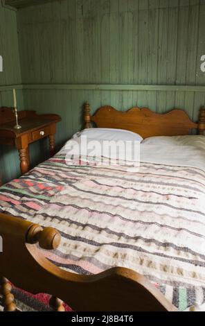 Antikes Bett und Nachttisch im Schlafzimmer im alten, ca. 1730. Jahre alten französischen Regime Maison Drouin, Sainte-Famille, Ile d'Orleans, Quebec, Kanada. Stockfoto