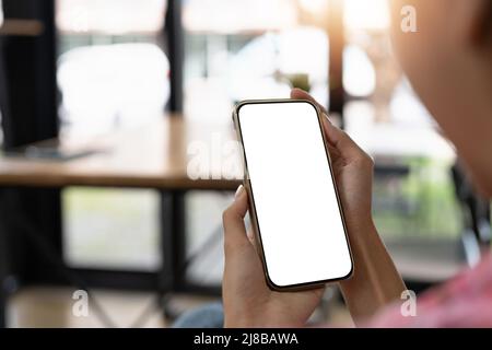 Nachbildung einer schönen Frau, die ein Mobiltelefon mit leerem weißen Bildschirm hält und zeigt. Stockfoto