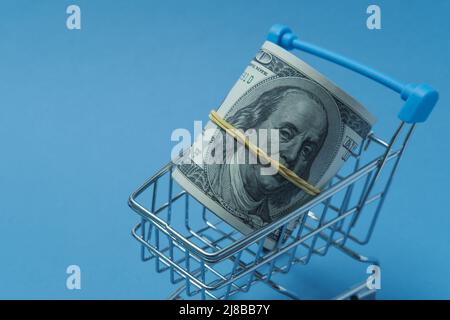 In einen Schlauch gerollte Dollars liegen in einem Einkaufskorb. Stockfoto