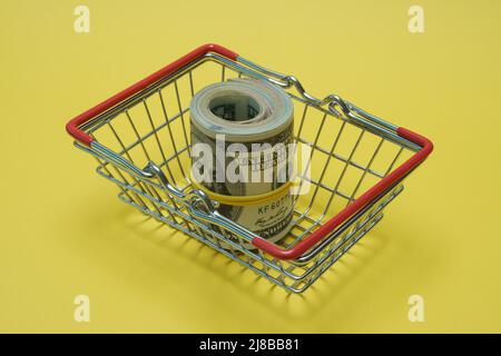 In einen Schlauch gerollte Dollars liegen in einem Einkaufskorb. Stockfoto