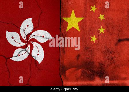 Gebrochene, rissige Betonwand mit bemalten chinesischen oder hongkonger Nationalflaggen. Konzept der Politik, wirtschaftliche Konflikte. Stockfoto