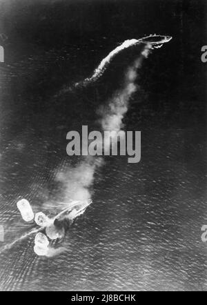 Verlust der HMS Prince of Wales und der HMS Repulse, 10. Dezember 1941: Aufnahme eines japanischen Flugzeugs während des ersten hochrangigen Bombenangriffs. Der Battlecruiser Repulse, am unteren Rand der Ansicht, wurde gerade von einer Bombe getroffen und von mehreren weiteren beinahe verpasst. Das Schlachtschiff Prince of Wales befindet sich ganz oben im Bild und erzeugt eine beträchtliche Menge Rauch. Stockfoto