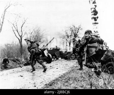 Deutsche Truppen marschierten während der Bulge-Schlacht an verlassenen amerikanischen Geräten vorbei. Stockfoto