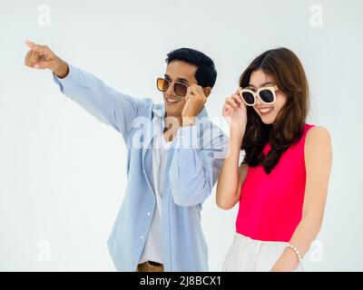 Paar Reisende, glücklicher Urlaub und Sommerurlaub. Das asiatische Paar trägt eine Sonnenbrille, zeigt und freut sich auf spannende, junge Frau und Mann mit Stockfoto