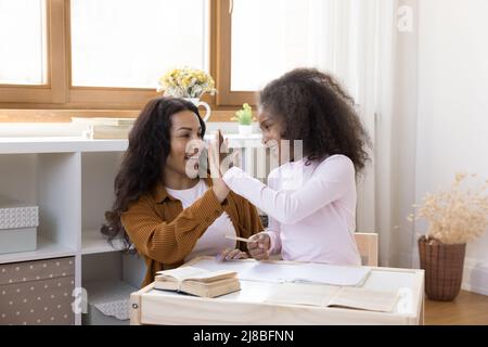 Afrikanische Mutter lobte die kleine Tochter für den erfolgreichen Abschluss der Schularbeit Stockfoto