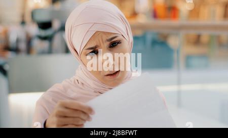 Nahaufnahme junge muslimische Frau in Hijab öffnet Papierbrief liest schlechte Nachrichten schockiert fühlt sich enttäuscht traurig arabischen Mädchen erfährt, dass gescheiterte Prüfungen bekommen Stockfoto