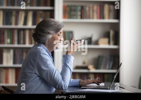 Glückliche selbstbewusste reife Geschäftsfrau, die ein Mobiltelefon anruft Stockfoto