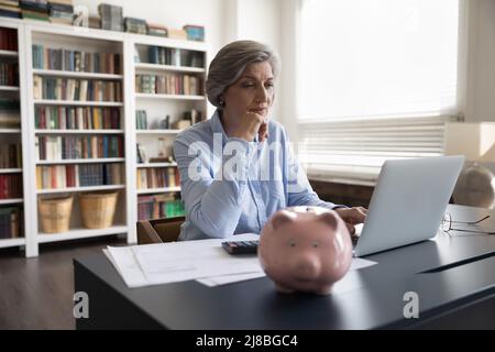 Fokussierte Geschäftsfrau mittleren Alters, die Rechnungen zahlt Stockfoto