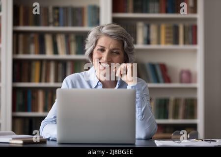 Glückliche, reife Geschäftsfrau, die bei einem Videoanruf am Laptop spricht Stockfoto