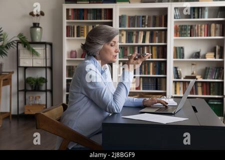Fokussierte Geschäftsfrau, die eine Audionachricht auf dem Mobiltelefon aufzeichnet Stockfoto