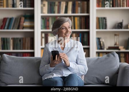 Fröhliche ältere grauhaarige Frau mit Handy Stockfoto