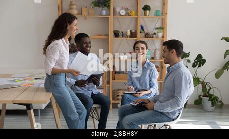 Fröhlich aufgeregt multiethnischen Business-Gruppe Brainstorming, Austausch von lustigen Ideen Stockfoto