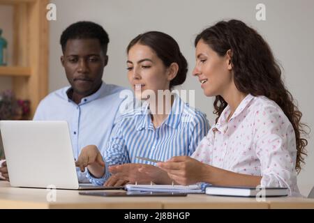 Selbstbewusste Praktikanten für die Ausbildung von Lehrern im Unternehmen, die ein Notebook teilen Stockfoto