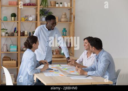 Glücklicher, erfolgreicher afrikanischer Teamleiter, der ein Unternehmensmeeting veranstaltet Stockfoto