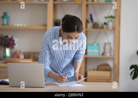 Fokussierte beschäftigt tausendjährige Unternehmerin Frau Unterzeichnung Papier Dokument Stockfoto