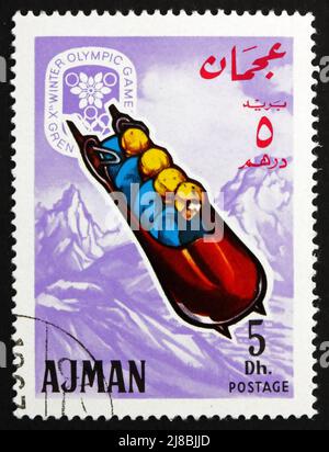 AJMAN - UM 1967: Eine im Ajman gedruckte Marke zeigt vier-Mann-Bobsled, Olympische Winterspiele 68, Grenoble, um 1967 Stockfoto