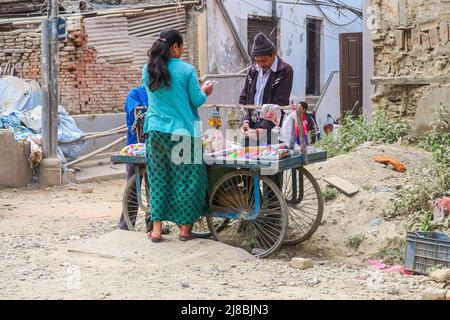 Kathmandu, Nepal - 27. Oktober 2021: Straßenhändler verkauft seine Penny-Waren in den Ruinen der vom Erdbeben heimgesuchten Stadt. Frau überprüft die Waren der Stockfoto