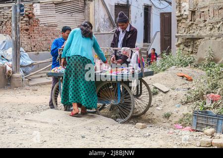 Kathmandu, Nepal - 27. Oktober 2021: Straßenhändler verkauft seine Penny-Waren in den Ruinen der vom Erdbeben heimgesuchten Stadt. Frau überprüft die Waren der Stockfoto