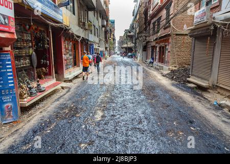 Kathmandu, Nepal - 27. Oktober 2021: Stadtbild der nepalesischen Hauptstadt. Eine ansonsten staubige Straße wird provisorisch mit Teer besprüht, um den Staub zu binden. Po Stockfoto