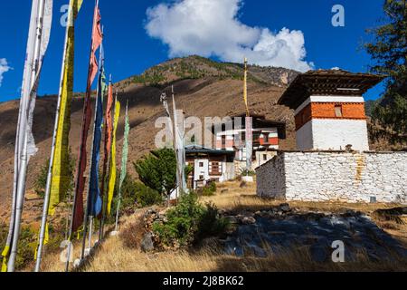 Bhutan - 23. Oktober 2021: Kleines Kloster oder Tempel in den hohen Bergen von Bhutan. Traditionelle bhutanische Architektur. Bunte Gebetsfahnen auf pol Stockfoto