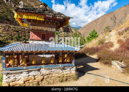 Bhutan - 23. Oktober 2021: Kleiner Tempel oder Stupa im Himalaya-Berg von Bhutan. Gebetsfässer unter blauem Dach. Traditionelle bhutanische Architektur Stockfoto