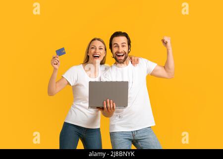 Zufrieden aufgeregt tausendjährigen kaukasischen Mann und Frau in weißen T-Shirts zeigen Sieg Geste und halten Kreditkarte Stockfoto