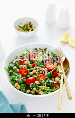 Vegetarischer Kichererbensalat mit Tomaten, Rucola, Petersilie, Spinat und roten Zwiebeln. Gesunde Ernährung, Ernährung Stockfoto