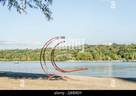 Roter Liegestuhl aus Metall am Strand der Donau. Stockfoto