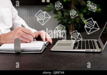 Geschäftsmann erhält eine Menge E-Mails, Kunden Anfragen. Mann, der sich im Planer Notizen gemacht hat, während er am Laptop arbeitete und nach neuen elektronischen Briefen überprüfte. Hochwertige Fotos Stockfoto