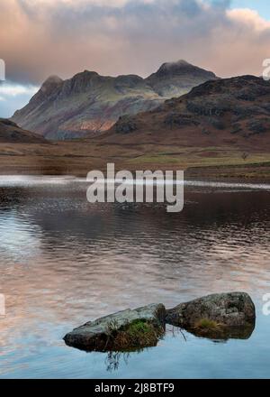 Epische Landschaft mit Sonnenaufgangslicht über Blea Tarn im Lake District mit atemberaubendem Licht auf fernen Bergen Stockfoto