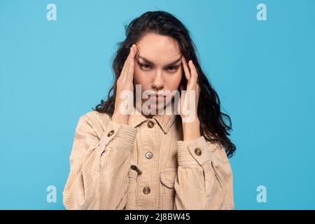 Traurig müde junge europäische Dame Brünette leidet unter Kopfschmerzen, drückt die Hände zu den Schläfen Stockfoto