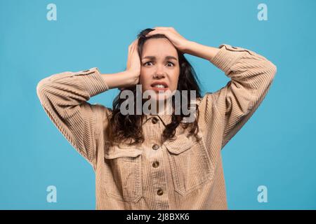 Schockiert verängstigt verärgert junge europäische Brünette Frau in lässig halten ihren Kopf mit den Händen Stockfoto
