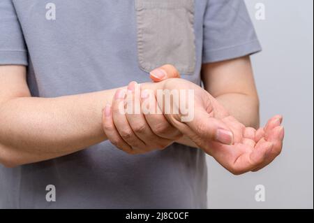 Ein Mann wickelte sich wegen Schmerzen am Handgelenk um sein Handgelenk. Ursachen für rheumatoide Arthritis, Karpaltunnelsyndrom, Gicht. Gesundheitsfürsorge und medizinisches Konzept. Stockfoto