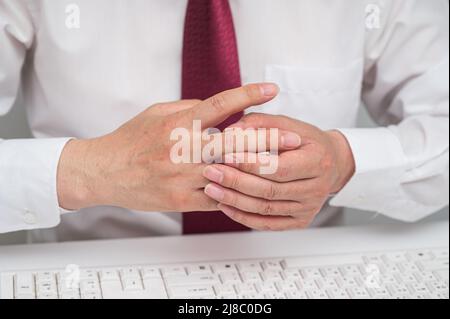 Hand eines Geschäftsmannes, der unter Schmerzen in den Fingergelenken leidet. Ursachen für rheumatoide Arthritis, Gicht. Gesundheitsfürsorge und medizinisches Konzept. Stockfoto
