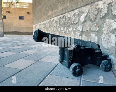 In der Altstadt steht eine kleine antike Kanone auf Rädern auf dem Boden. Stockfoto