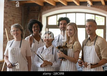 Eine Gruppe von Leuten, die Pinsel halten, posieren in der Werkstatt des Kunststudios Stockfoto