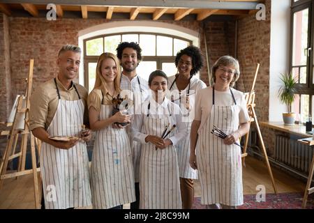 Gruppe von multiethnischen Menschen, die im Atelier der Kunstschule Pinsel in der Hand halten Stockfoto